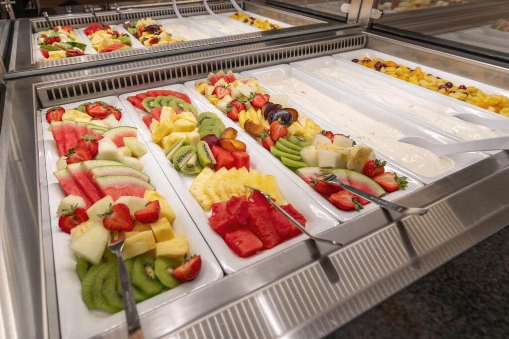 Viele verschiedene Obstsorten und cremiger Joghurt liegen ansprechend drapiert in der Buffet-Theke.