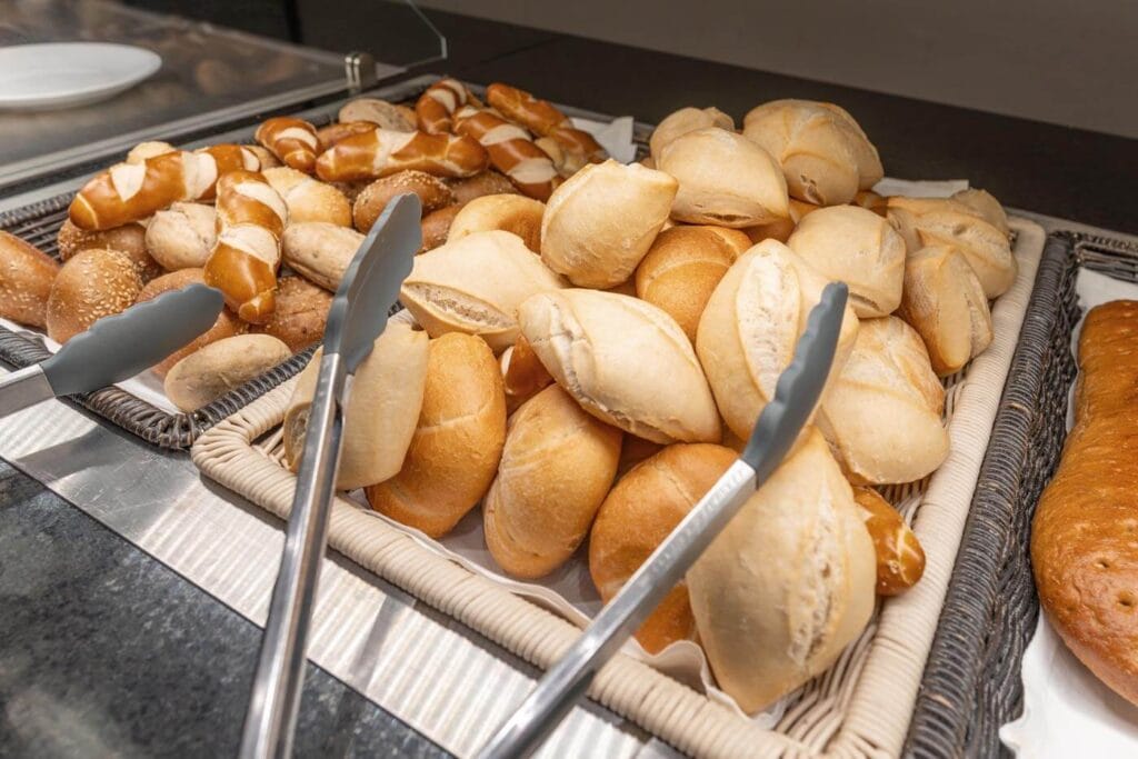 Verschiedene Sorten frischer Brötchen liegen in Körben der Frühstückstheke.
