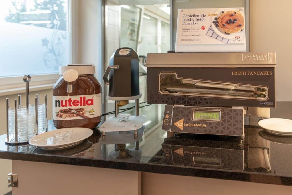 Man sieht die Attraktionen des Frühstsücks, ein riesiger Nutella-Spender und ein Pancake-Automat.