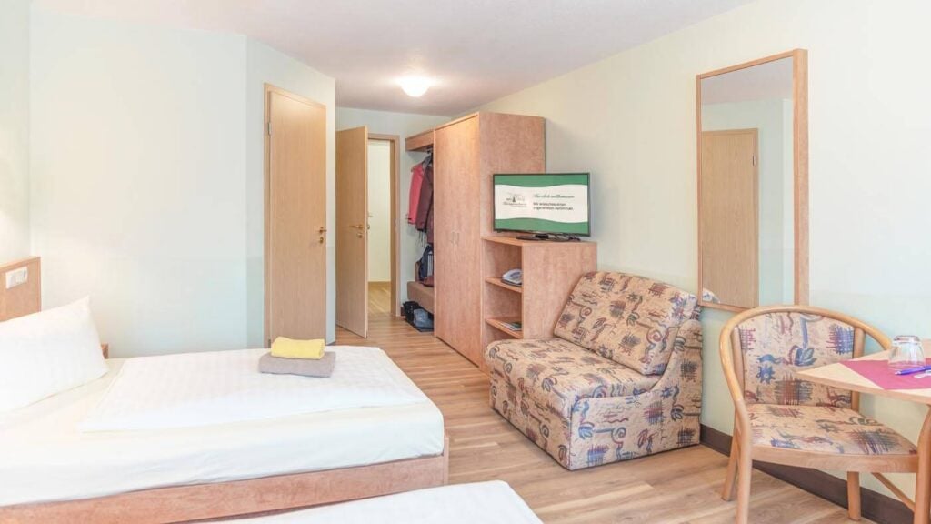 Blick in das Twinbett-Zimmer in Richtung TV, Schrank und Badezimmertür.